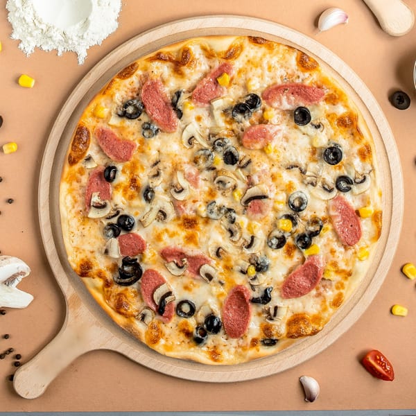 Paras Pizza & Gyro's pizza with sausage, mushrooms, olives, and corn on a wooden board.